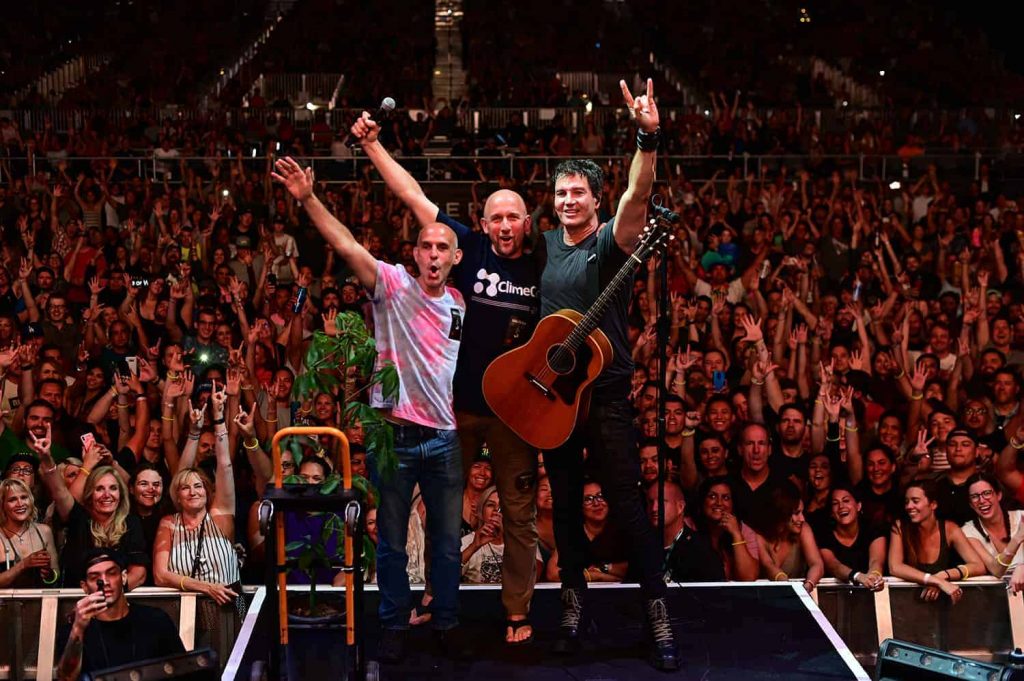 Three people on stage with people behind.