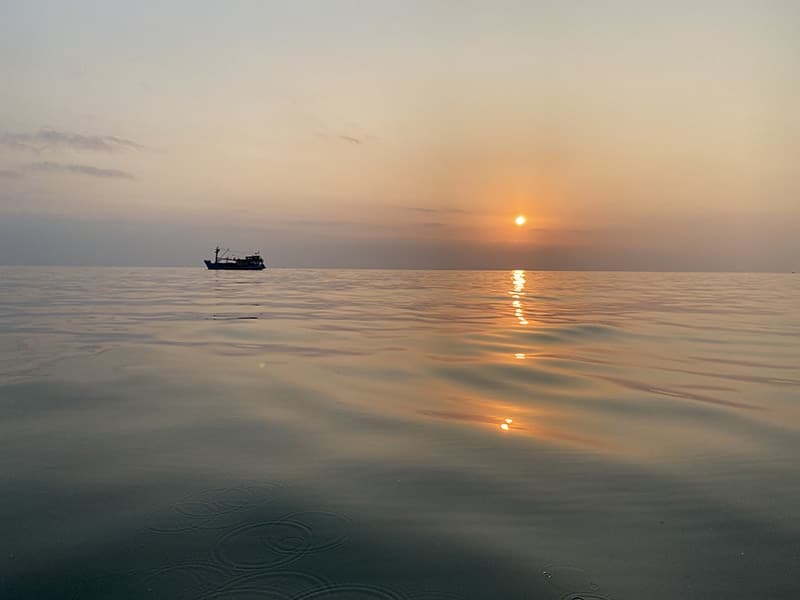 Boat on water with a sunset behind
