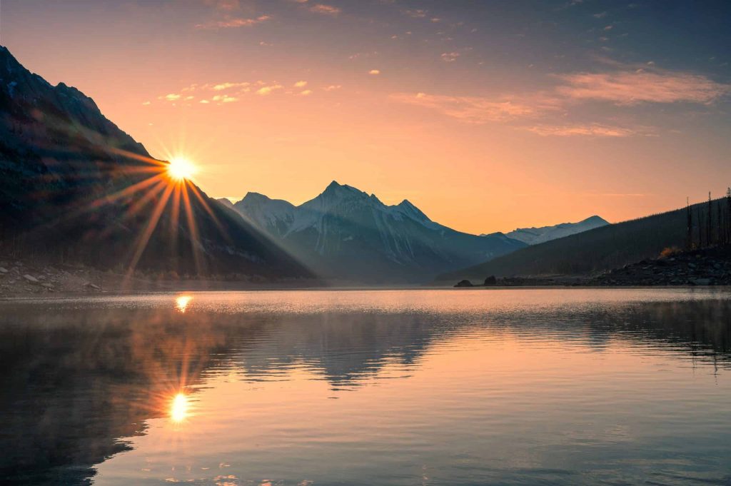 Sun shining over a lake within the mountains
