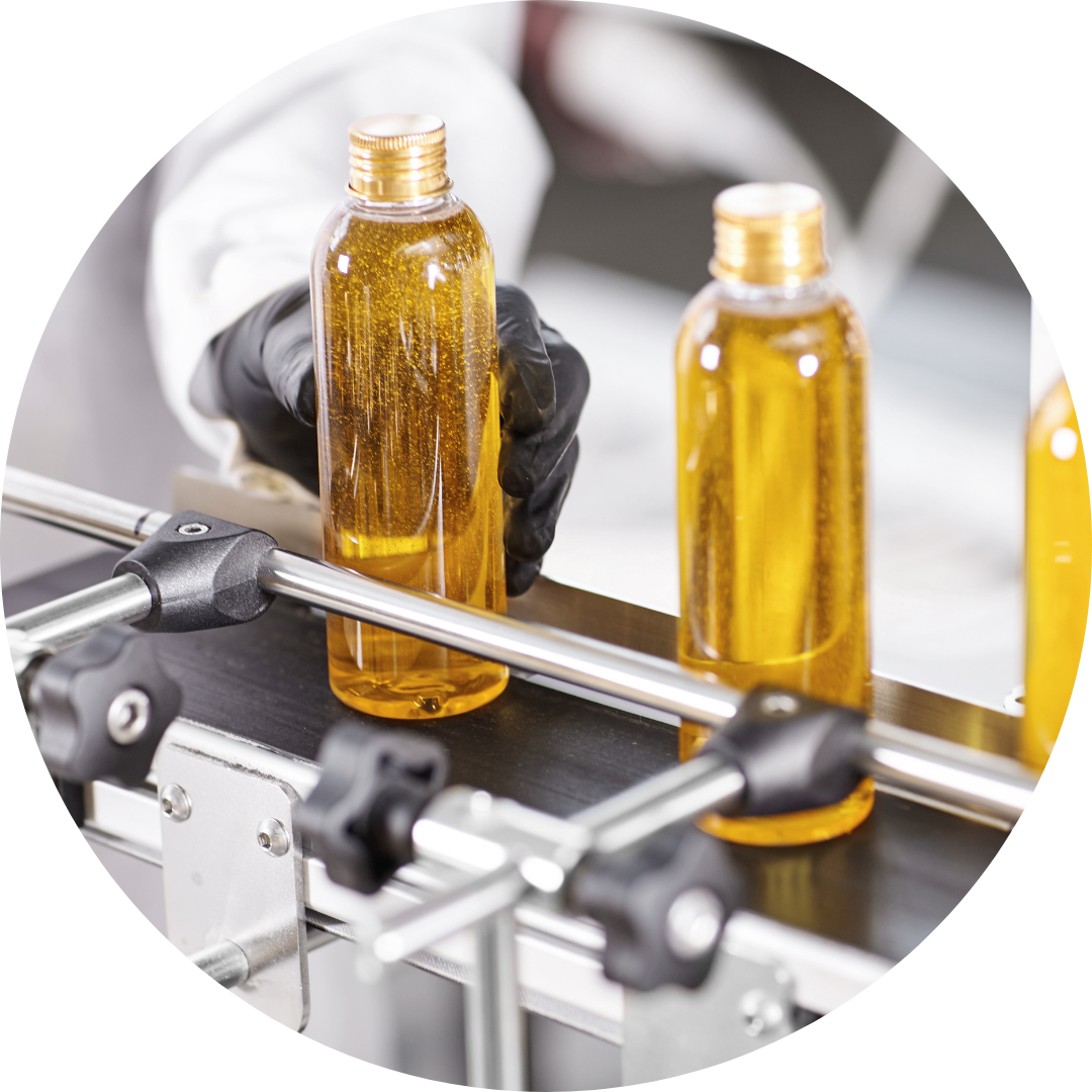 Three glass bottles filled with liquid on a conveyor belt